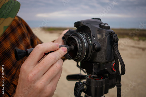 Photographer Cleaning Lens of Camera on a Tripod