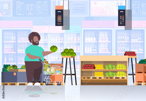 fat obese man with shopping trolley cart choosing vegetables and fruits overweight african american guy supermarket customer weight loss concept grocery shop interior horizontal full length