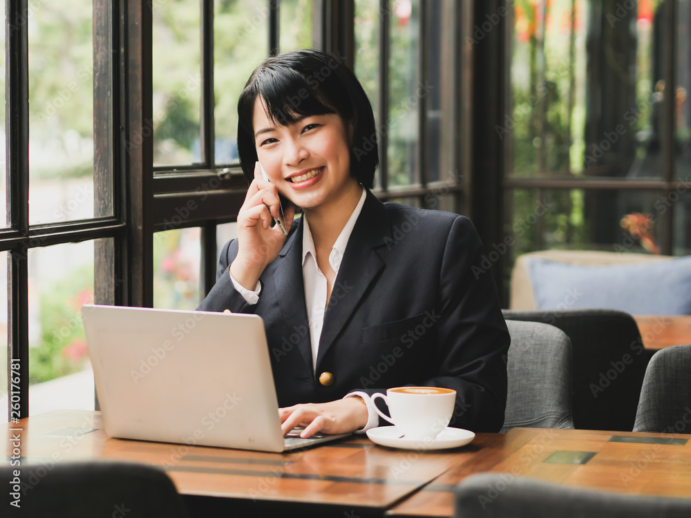 Asian woman using laptop and drinking coffee in coffee shop cafe Asian woman using laptop and drinking coffee in coffee shop cafe