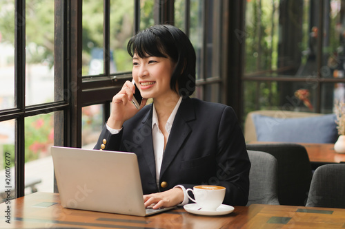 Asian woman using laptop and  drinking coffee  in coffee shop cafe