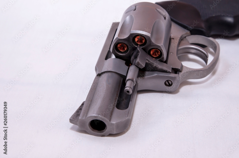 A stainless steel snub nosed 357 magnum revolver loaded with hollow point bullets on a white background