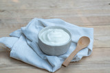 Natural homemade plain organic yogurt in ceramic bowl on wood texture background