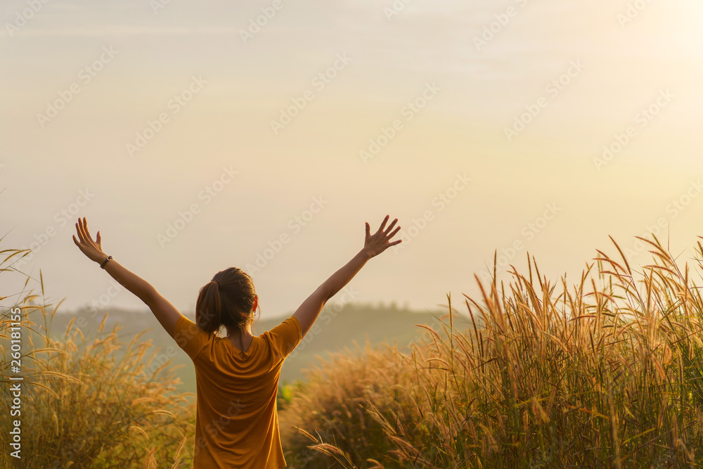 Asian woman standing in meadow and show hand up at sunrise time, Selective focus, Copy space. Asian woman standing in meadow and show hand up at sunrise time, Selective focus, Copy space.