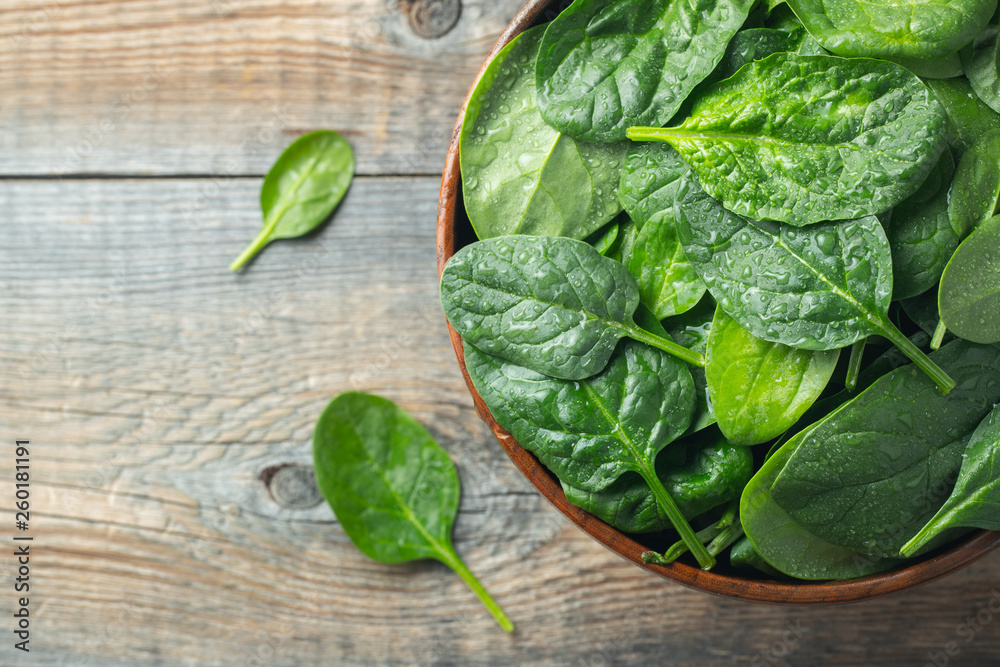 Fresh spinach leaves in bowl on wooden table. Fresh spinach leaves in bowl on wooden table.