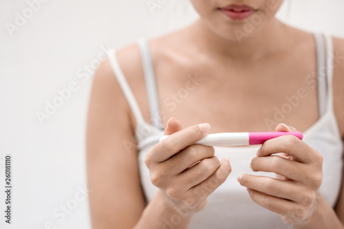 Unhappy young asian woman holding pregnancy test showing a negative result in her bathroom, wellness and healthy concept, infertility problem,Selective focus.