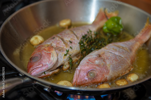 Fotografía Red snapper fish being fried in frying pan on stove