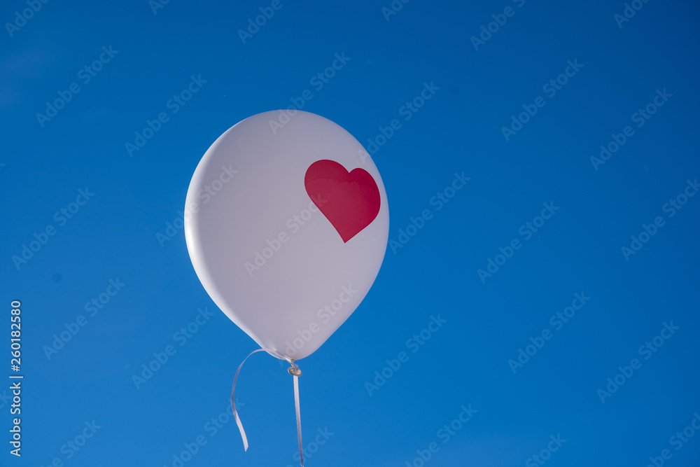 white balloon with red heart on clear blue sky background white balloon with red heart on clear blue sky background
