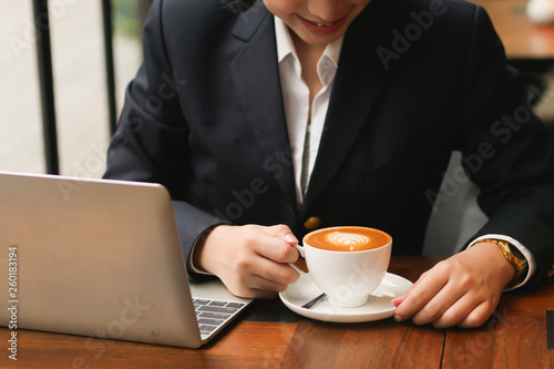 Asian woman using laptop and drinking coffee in coffee shop cafe