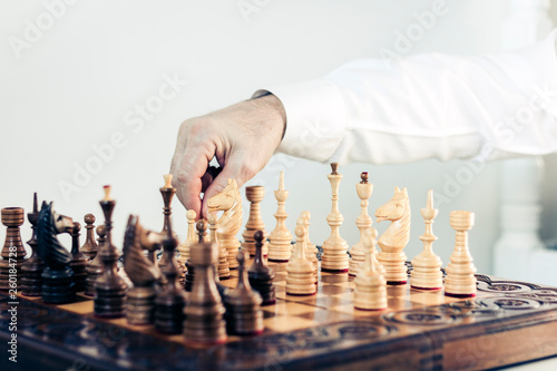 Wooden chess pieces on a chessboard, chess game player makes a move.