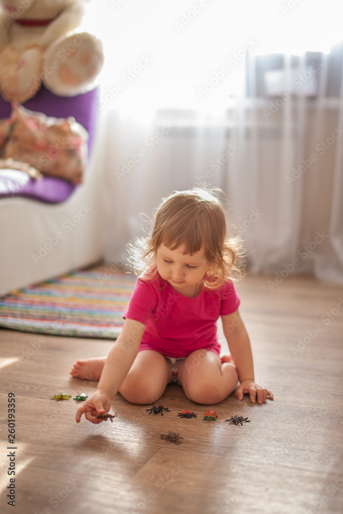 Little girl playing on the floor in the room in small toys Little girl playing on the floor in the room in small toys