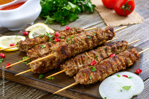 Delicious lula kebab on a wooden table. Chopped meat on wooden skewers, grilled. Eastern cuisine.