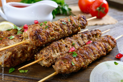 Delicious lula kebab on a wooden table. Chopped meat on wooden skewers, grilled. Eastern cuisine.