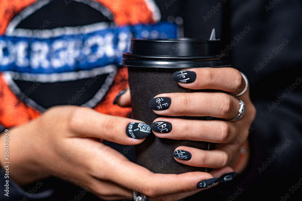 black matte manicure has different lettering with dark background 