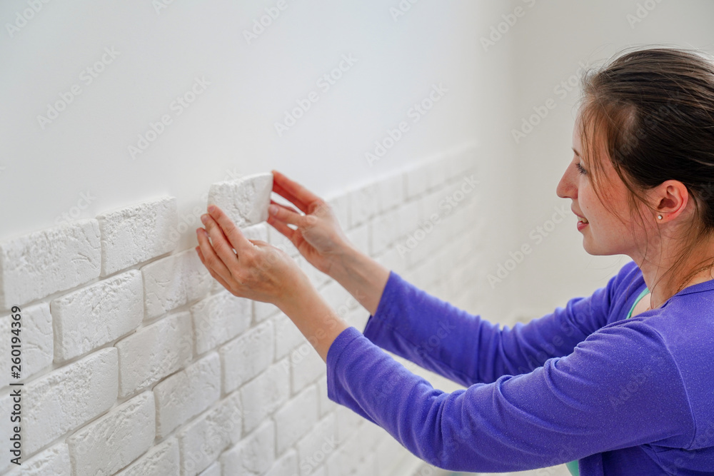 girl mounts decorative brick on the wall