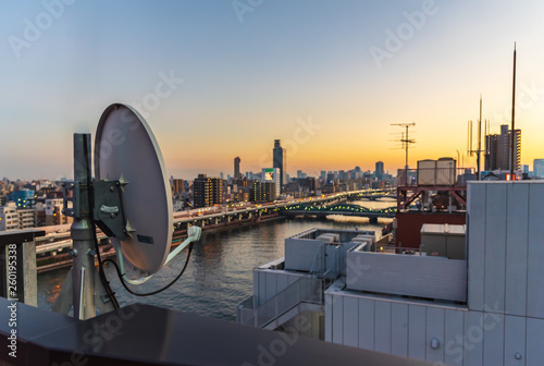 Slika na platnu Satellte dish at the top of building at sunset with a background of Sumida river and Tokyo city