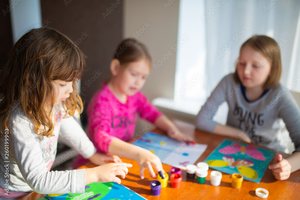 Three sisters little girls drawing with fingers on paper. Play, fun, childhood. Montessori school Three sisters little girls drawing with fingers on paper. Play, fun, childhood. Montessori school