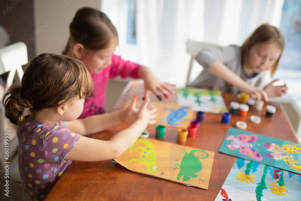 Three sisters little girls drawing with fingers on paper. Play, fun, childhood. Montessori school Three sisters little girls drawing with fingers on paper. Play, fun, childhood. Montessori school