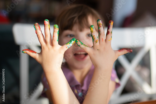 Cute little preschool girl looking at her painted hands.