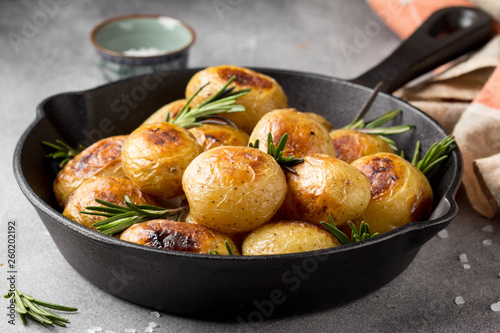 Vászonkép Fried (baked) whole small potatoes with rosemary and salt in a frying pan, ruddy