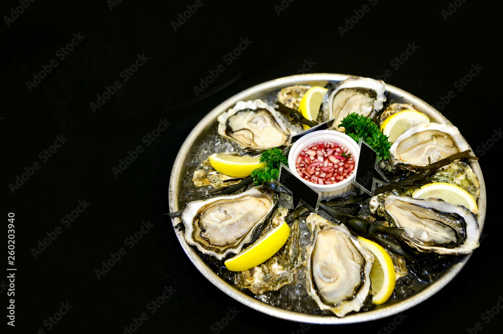 Fresh oysters on a plate with ice and lemon slices