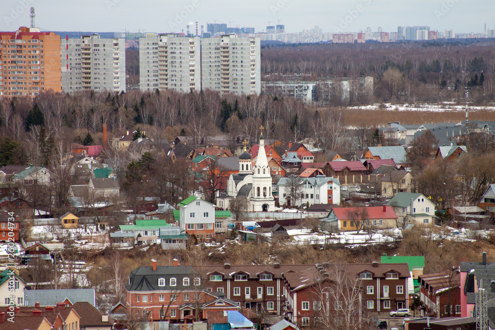 church among low houses against the background of multystoried buildings in Troitsk Moscow