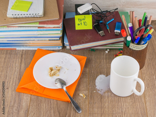 mess the student-dirt: Cup, crumbs of cake and a teaspoon of orange on a napkin on a plate, spilled milk and crumbs of the cake scattered on the desktop