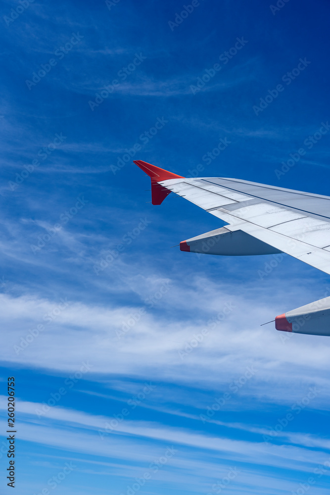 Fototapeta premium Wing of airplane flying above the white clouds in the blue sky . The theme of tourism and travel