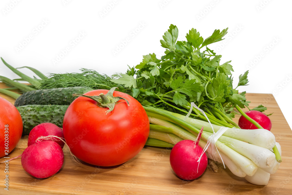 Fresh vegetables and greens on bamboo cutting board close-up Fresh vegetables and greens on bamboo cutting board close-up