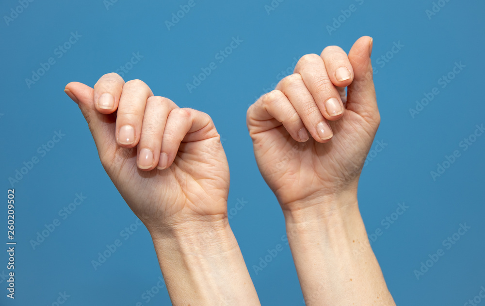young woman showing hands on blue background. Attractive presentation of hands and nails young woman showing hands on blue background. Attractive presentation of hands and nails