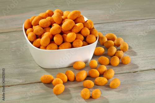 Peanut chips in white bowl on wooden background