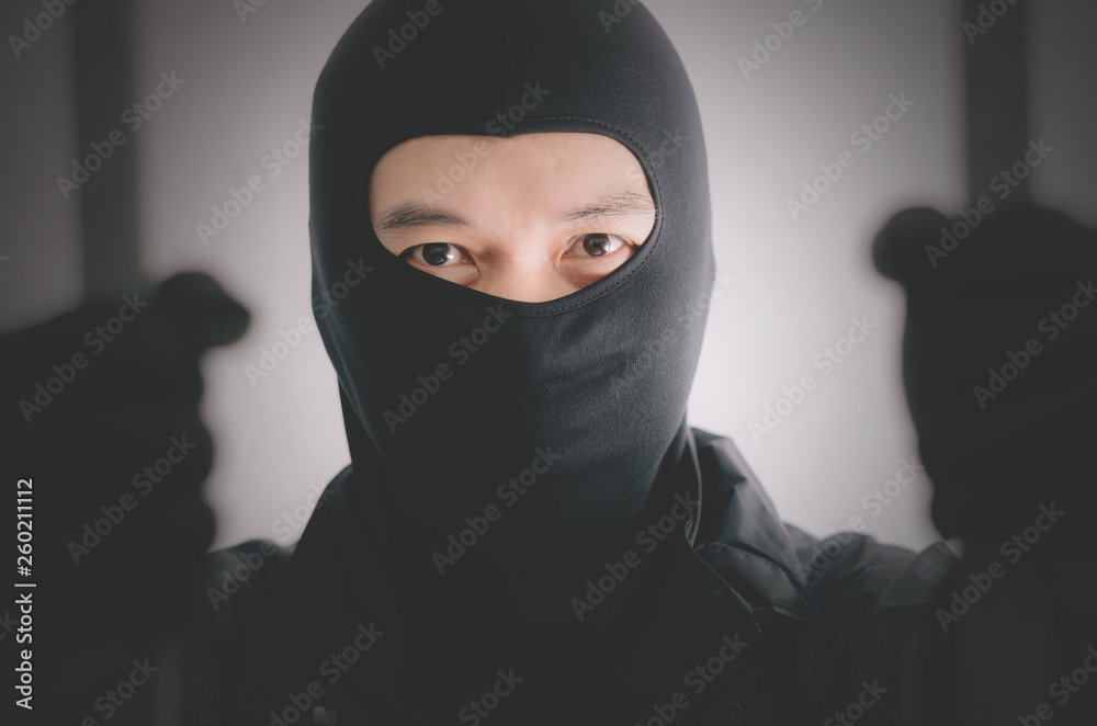 Bandit wearing a mask is agitated prisoner in jail holding bars isolated on white background. Bandit wearing a mask is agitated prisoner in jail holding bars isolated on white background.