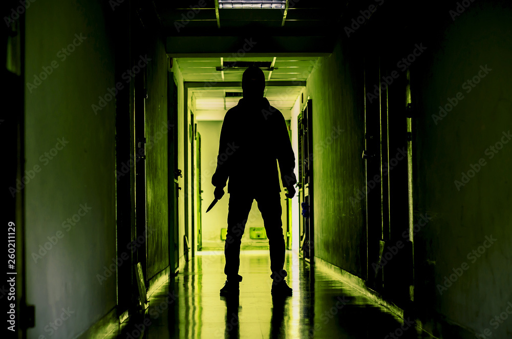 murder, kill and people concept - Criminal or murderer wearing a mask in silhouette holding knife inside a condo at crime scene.
