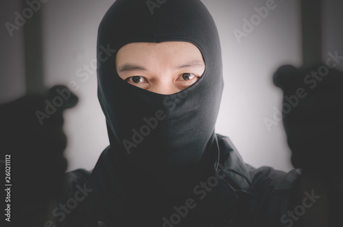 Bandit wearing a mask is agitated prisoner in jail holding bars isolated on white background.