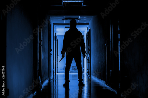 murder, kill and people concept - Criminal or murderer wearing a mask in silhouette holding knife inside a condo at crime scene.