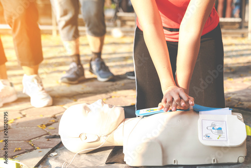 Asian female or runner woman training CPR demonstrating class in park by put hands and interlock finger over CPR doll give chest compression. First aid training for heart attack people or lifesaver. photo