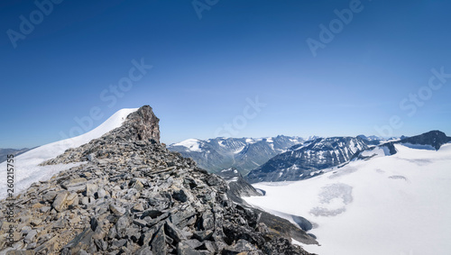 Hiker near the top of mountain in big panorama of Jotunheimen National Park Noway