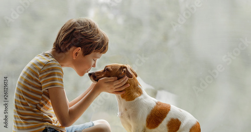 Child kisses the dog in nose on the window. photo