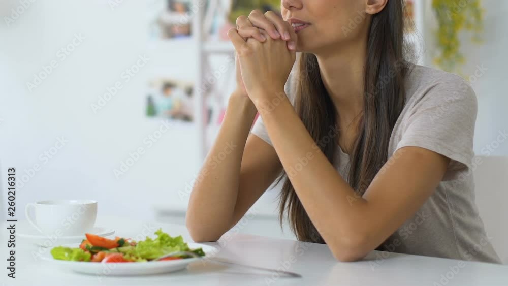 Young woman praying before eating, asking god to bless food, faith, christianity Young woman praying before eating, asking god to bless food, faith, christianity