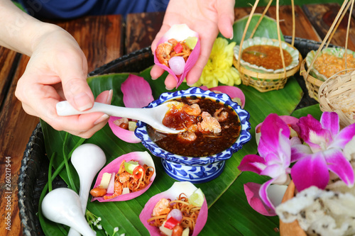 Woman's Hand Holding Fresh Lotus Petal Wrapped Appetizer while Scooping Out Spicy Dip