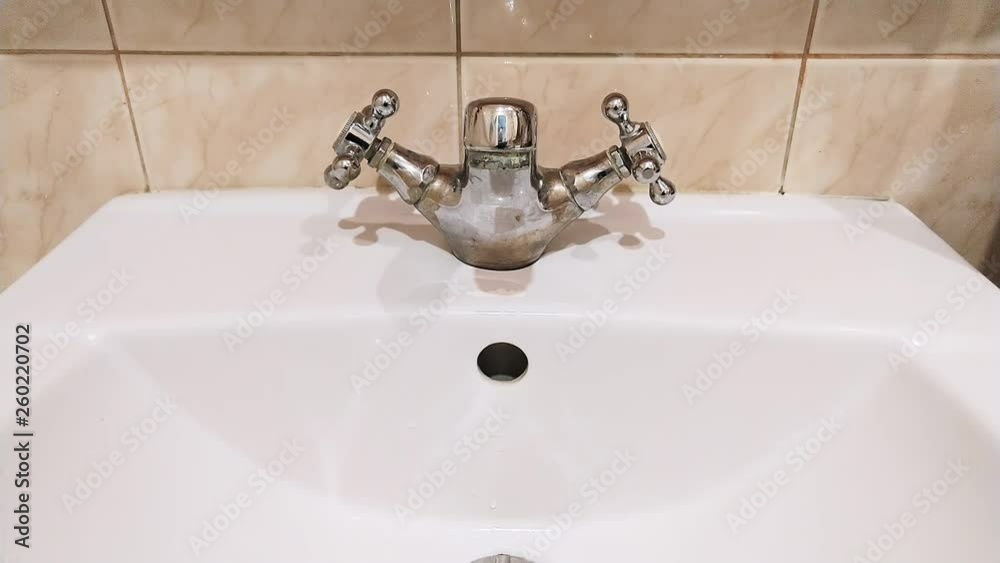 Drip of flowing water from the bathroom tap during a period of scarcity. Slow motion 4K video Drip of flowing water from the bathroom tap during a period of scarcity. Slow motion 4K video