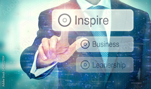 A business man selecting a button on a futuristic display with a Inspire concept written on it.