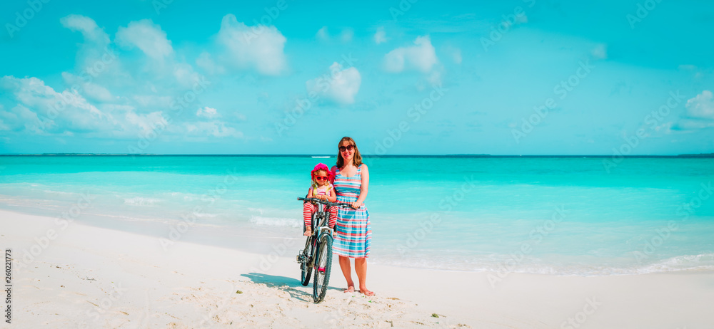 Happy mother with cute little baby girl bike at beach