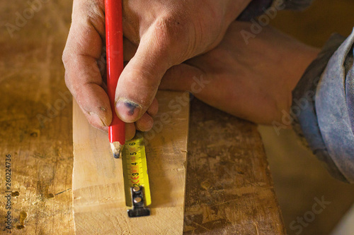 measuring with a centimeter and a pencil by a carpenter in a woodworking workshop