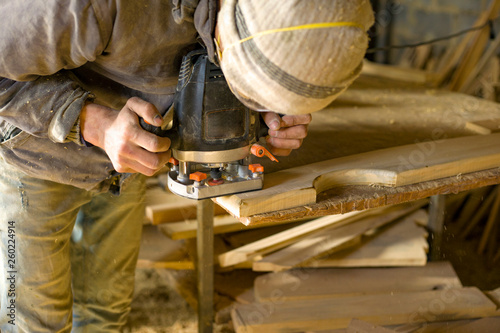 A man mills woodworker  in a woodworking workshop, a carpenter in a respirator with a milling machine