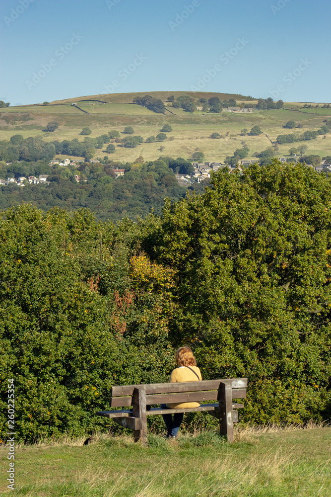 A woman sits enjoying the view of hills in the distance A woman sits enjoying the view of hills in the distance