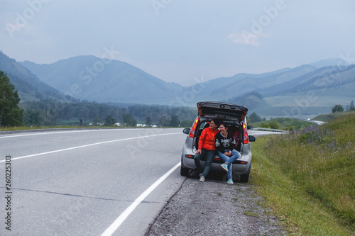 Two young brunette sitting in the car smiling and looking around. Travel concept