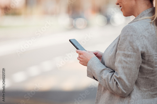 Business, technology and people concept. Businesswoman using smartphone in the city, close-up.