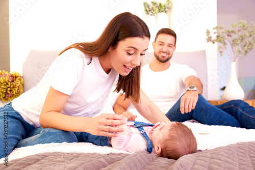 Happy young family relaxing in bad and playing together with their baby girl
