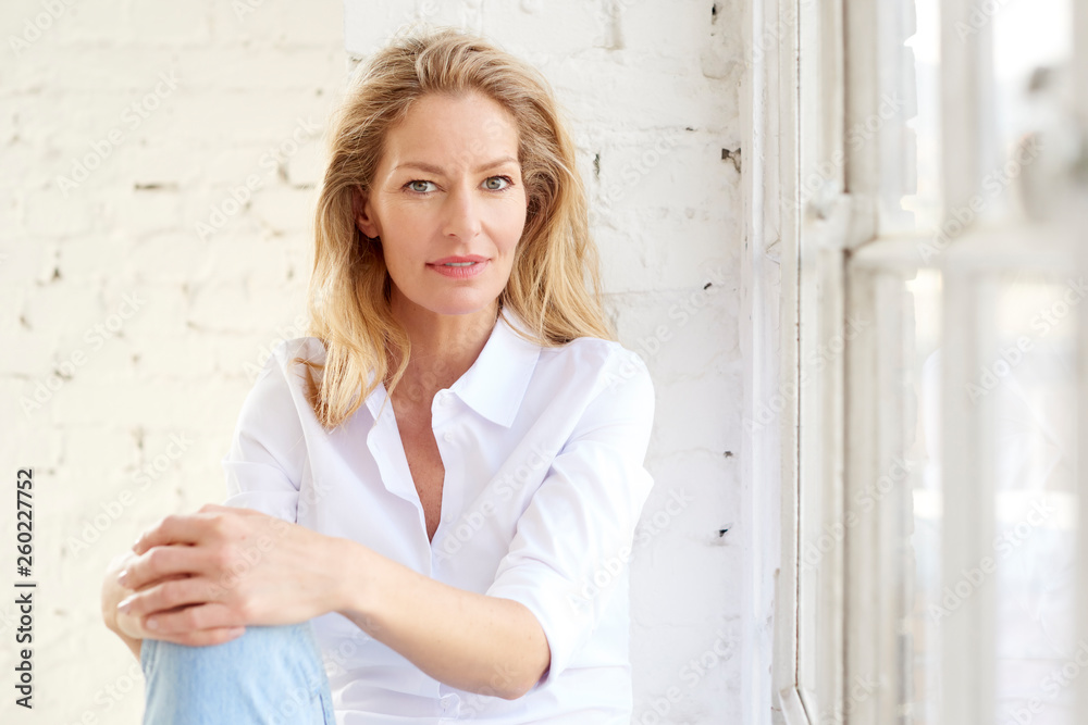 Fototapeta premium Attractive mature woman portrait while relaxing at the window