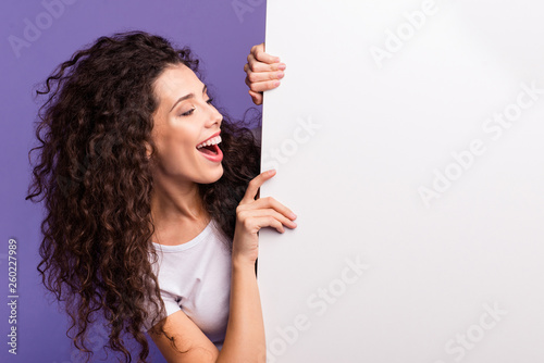 Close-up portrait of nice cute attractive charming cheerful cheery brunette wavy-haired lady showing looking aside large ad advert isolated over bright vivid shine violet purple background photo